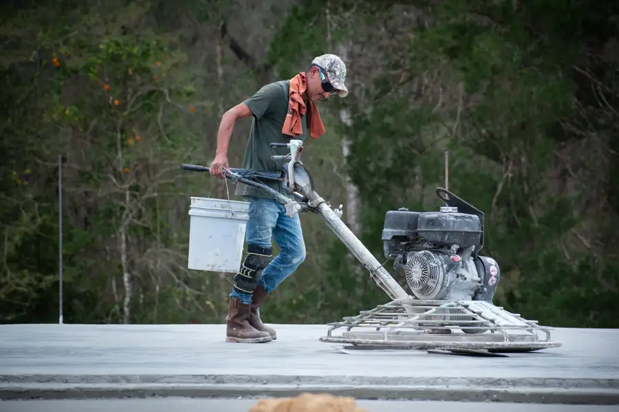 Worker using pickaxe to break up concrete during demolition phase of construction project